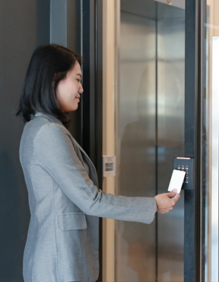 jeune femme tenant une carte-clé pour verrouiller et déverrouiller la porte d’entrée